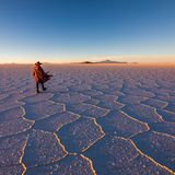 Mann läuft durch die Salar de Uyuni in Bolivien bei Sonnenuntergang