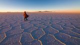 Mann läuft durch die Salar de Uyuni in Bolivien bei Sonnenuntergang