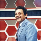 Quizmaster Hans Rosenthal lacht, gekleidet in ein blaues Jackett, in die Kamera