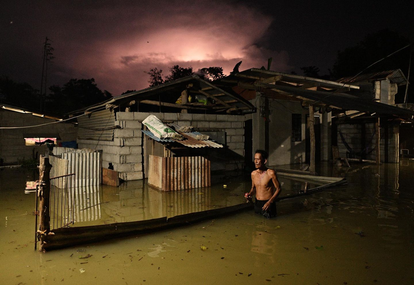 "Four Storms, Ten Days" von Noel Celis Mann läuft durch überflutete Straße auf den Philippinen