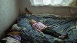 Geflüchtetes Mädchen aus der Ukraine auf einem Bett