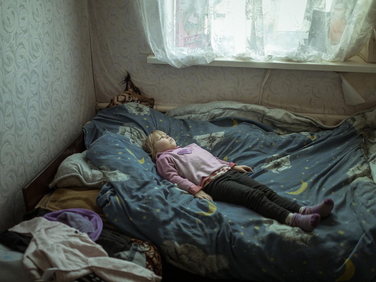 Geflüchtetes Mädchen aus der Ukraine auf einem Bett