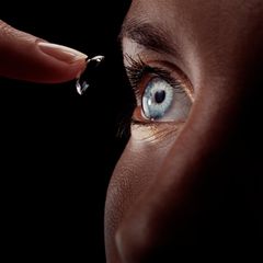 Frau setzt sich Kontaktlinse ein