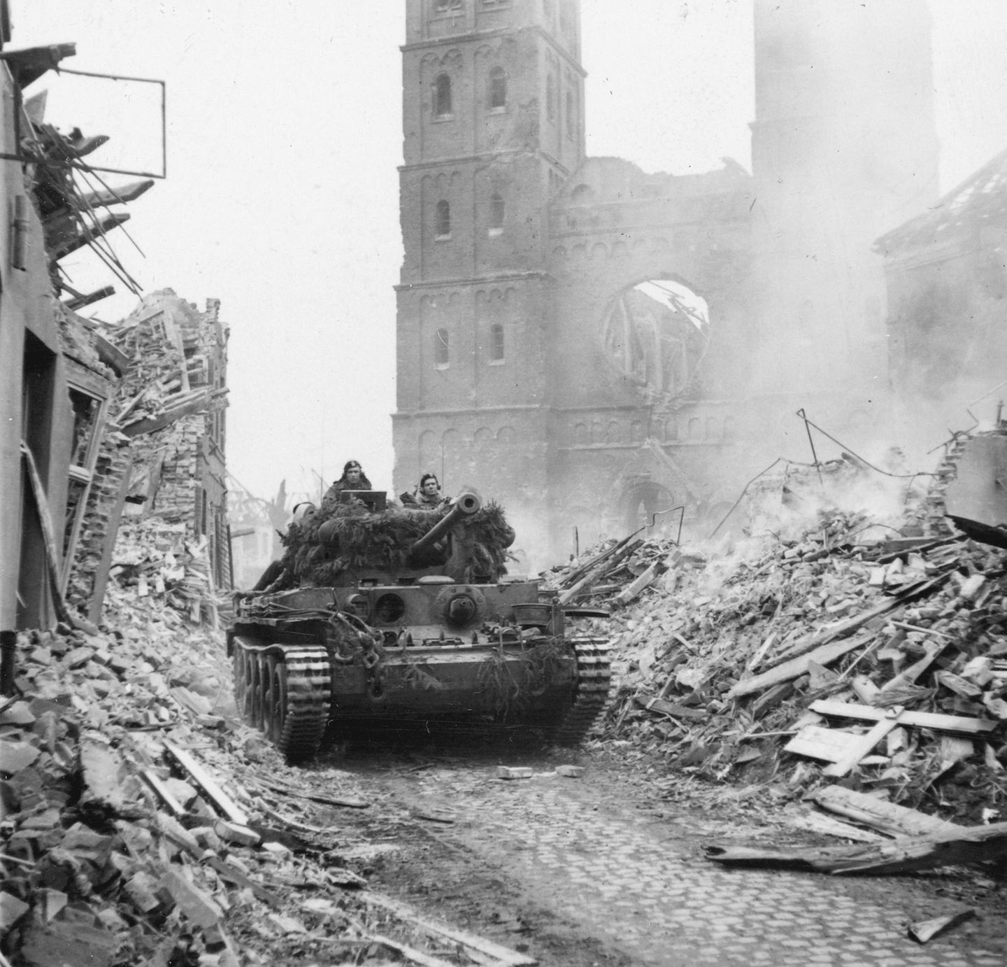 Ein Panzer fährt in einer Stadt zwischen Trümmern hindurch