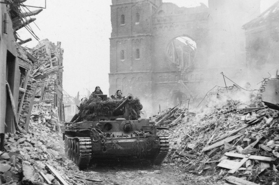 Ein Panzer fährt in einer Stadt zwischen Trümmern hindurch 1.0417