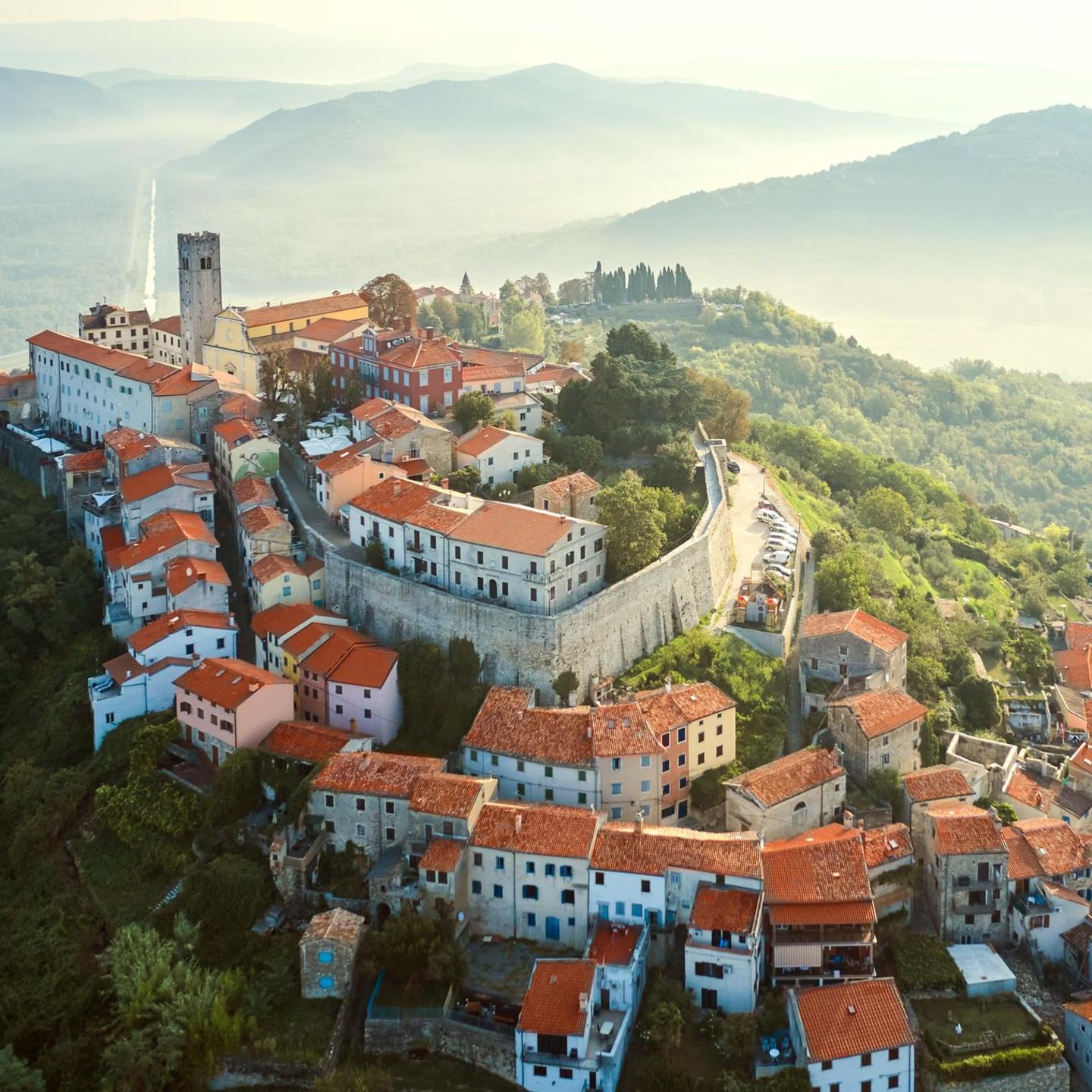 Altes Dorf auf einem Berg, dahinter Dunst und Hügelketten