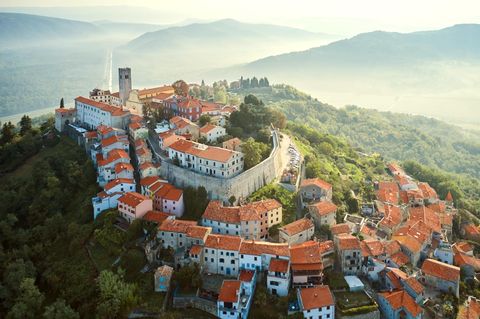 Altes Dorf auf einem Berg, dahinter Dunst und Hügelketten