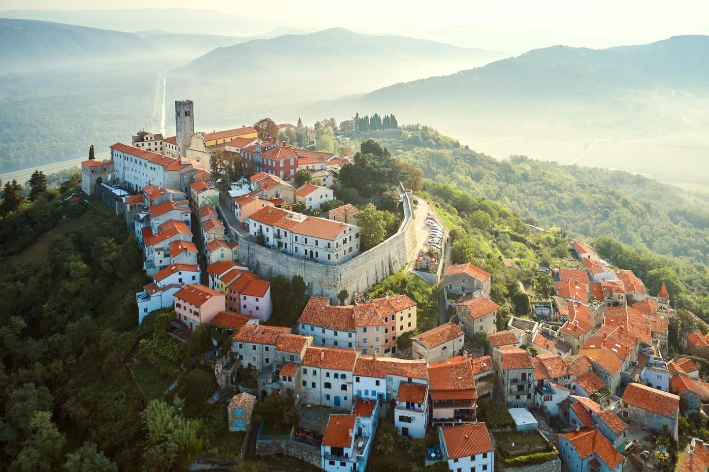Motovun: ein Dorf fast im Himmel Altes Dorf auf einem Berg, dahinter Dunst und Hügelketten