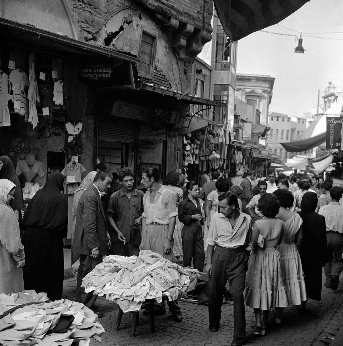 Der lange Weg in die Moderne Atatürk will auch die türkische Wirtschaft auf das Niveau westlicher Industriestaaten hieven, lässt Fabriken errichten und Maschinen kaufen. Doch der Rückstand der agrarischen und in vielen Regionen extrem strukturschwachen spätosmanischen Ökonomie ist nicht so schnell aufzuholen. In dieser Ladenstraße ist 1951 das Angebot an Kleidung reichhaltig, das Händler teils auf Tischchen und auf dem Boden ausgelegten Decken zeigen. Viele Geschäftsleute halten an alten Gewohnheiten fest, teils aus Überzeugung, teils aus Mangel an Geld oder Alternativen.