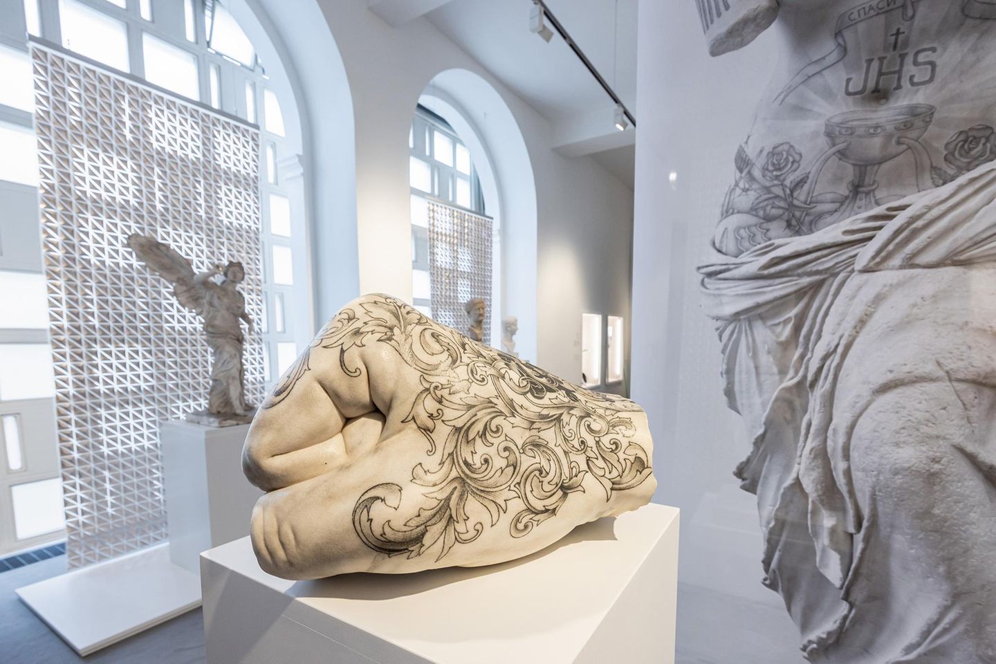 Eine geballte Faust – mit feinen Ornamenten Handplastik tätowiert im Ausstellungsraum
