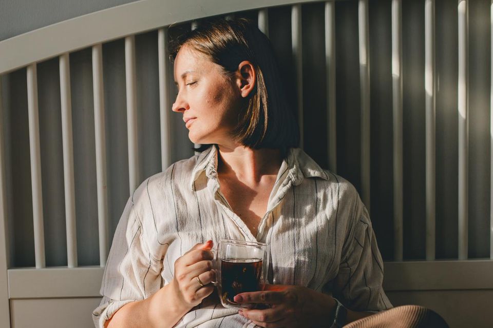 Frau sitzt auf dem Bett und trinke Kaffee 0.667