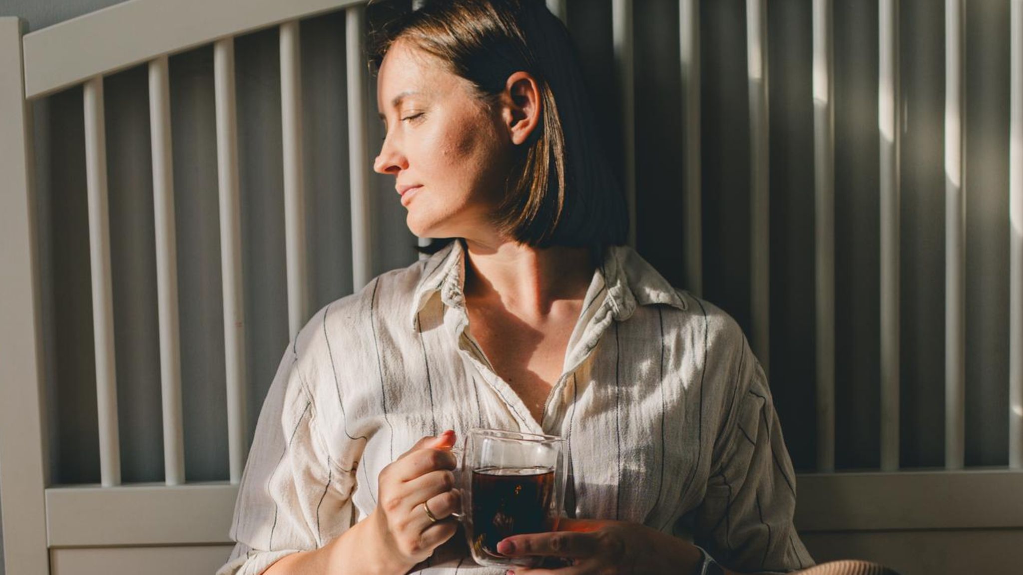 Frau sitzt auf dem Bett und trinke Kaffee