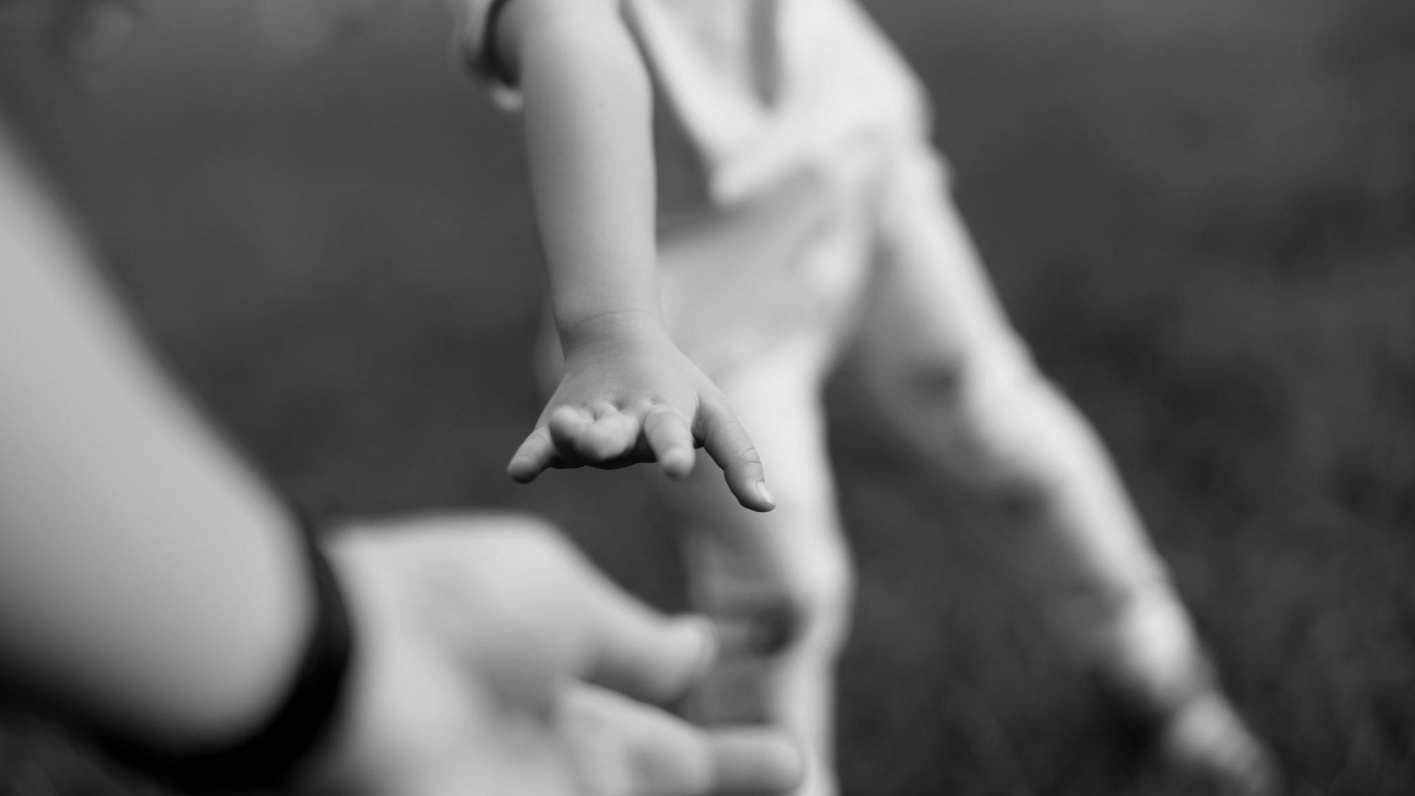 Kind streckt Hand nach Mann aus