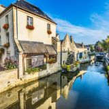 Blick auf Häuser in der Ortschaft Bayeux. Im Vordergrund Wasser