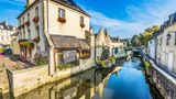 Blick auf Häuser in der Ortschaft Bayeux. Im Vordergrund Wasser