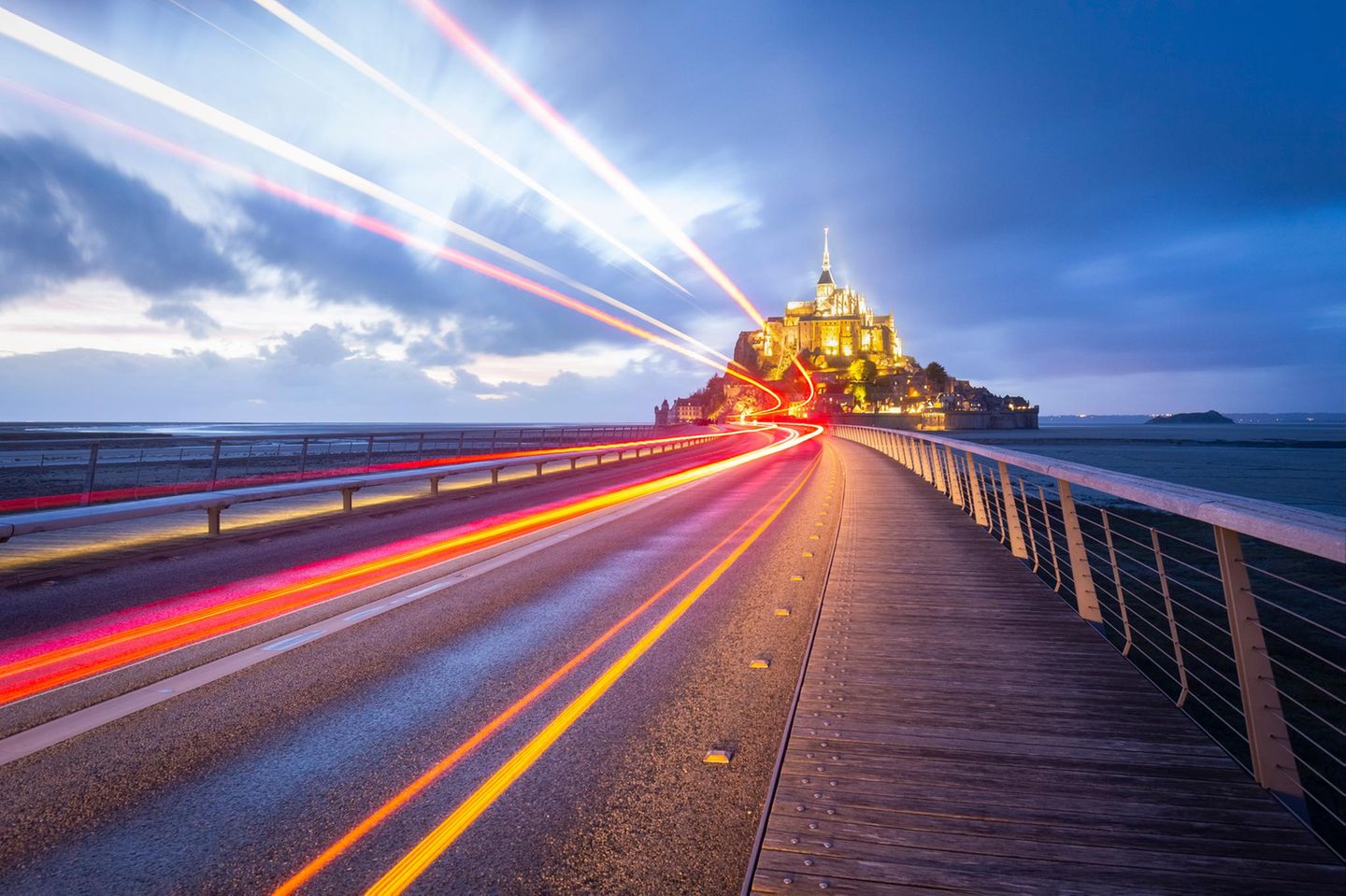 Der Klosterberg Mont Saint Michel zur blauen Stunde. Im Vordergrund eine Straße.