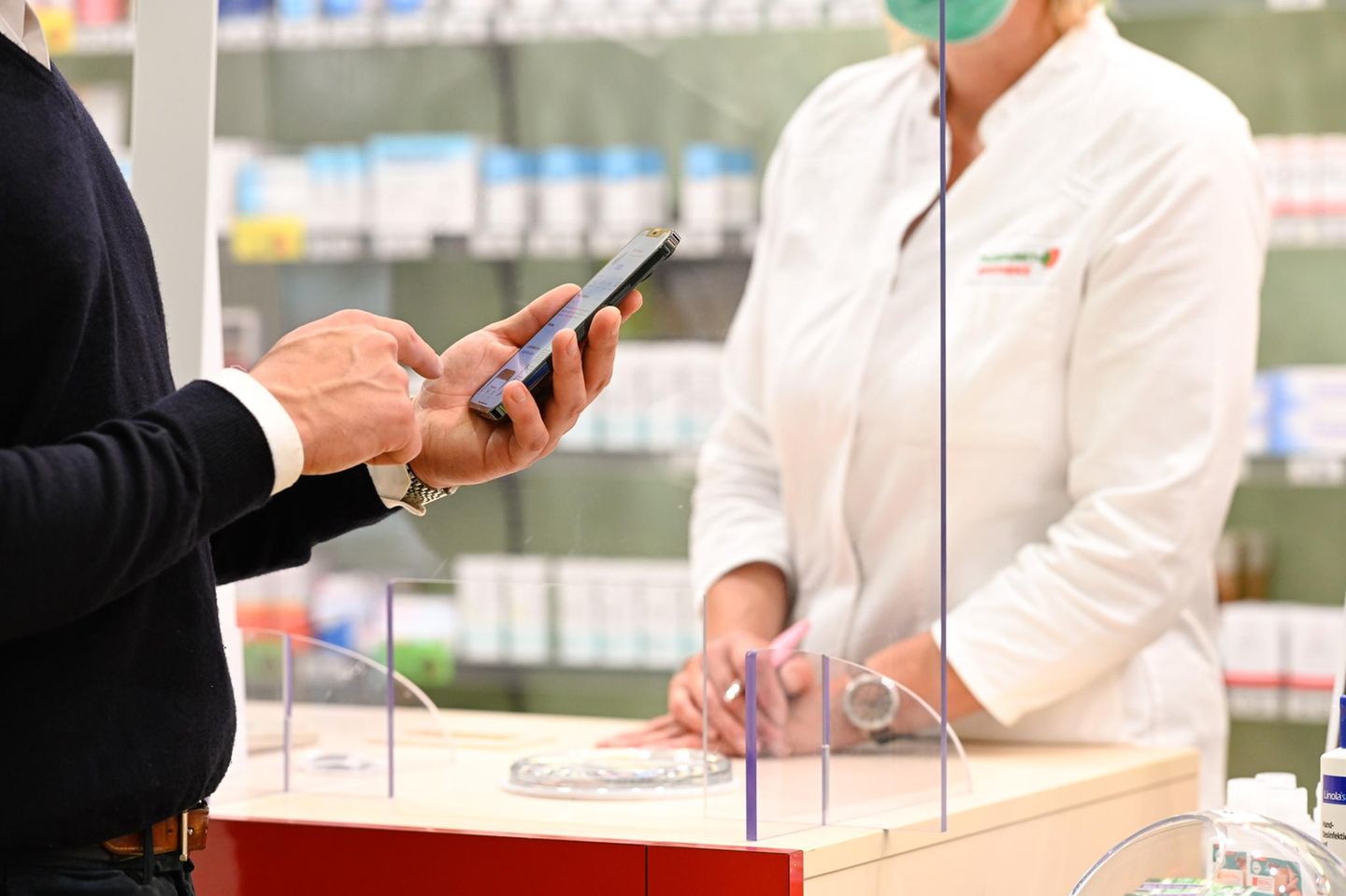 Mann hält Handy in einer Apotheke