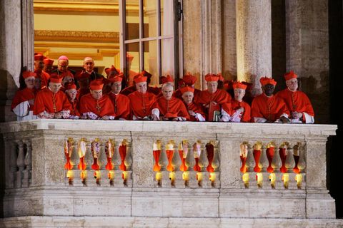Während sich Papst Franziskus 2013 kurz nach seiner Wahl zum ersten Mal der Öffentlichkeit zeigt, stehen auf einem benachbarten Balkon Kardinäle zusammen und verfolgen die Reaktion auf ihre überraschende Wahl