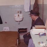 Ein Beamter schaut sich ein Loch in der Zellenwand an