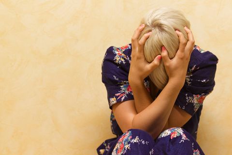 Frau mit Migräne hält ihren Kopf in den Händen