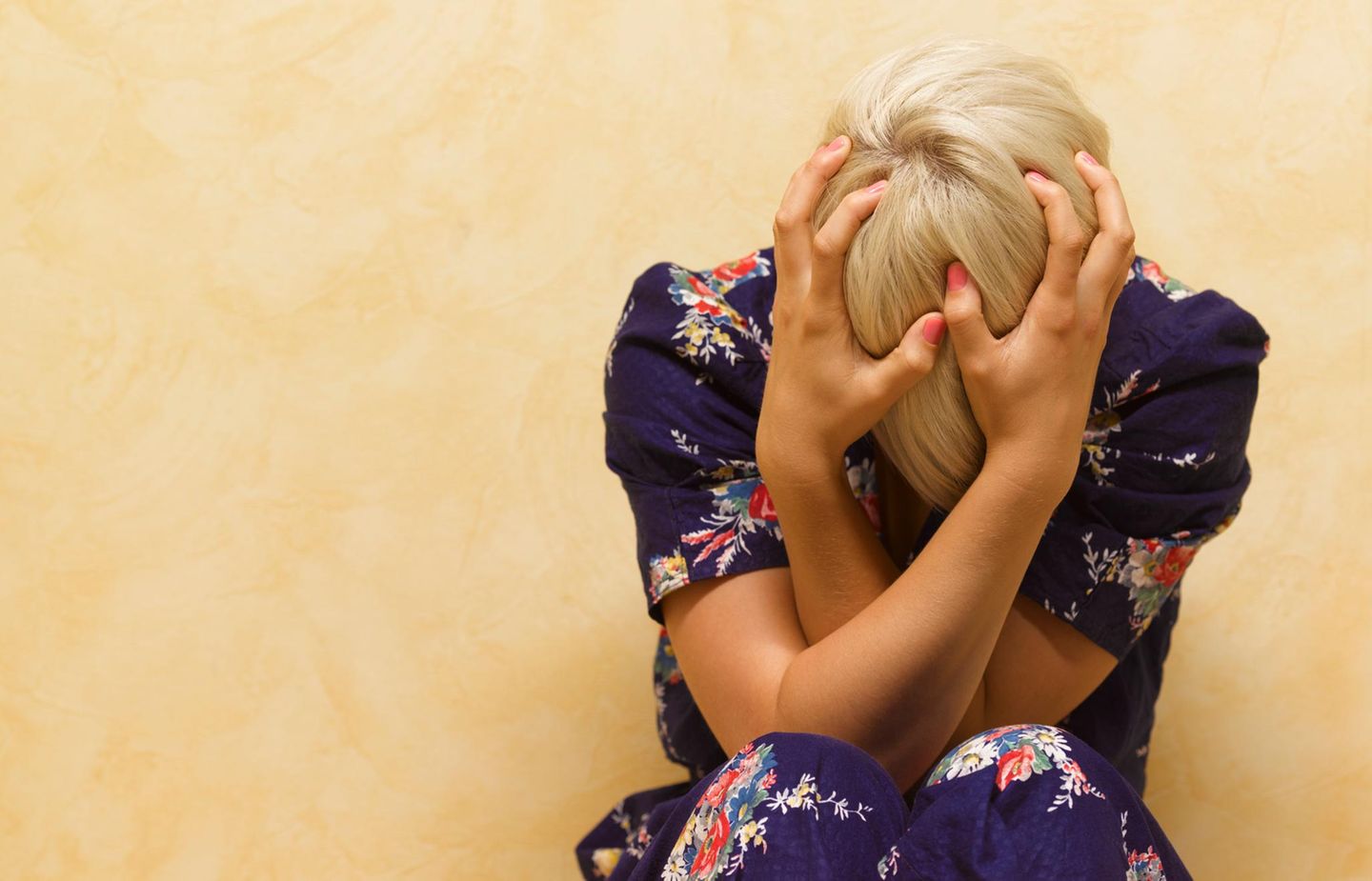 Frau mit Migräne hält ihren Kopf in den Händen
