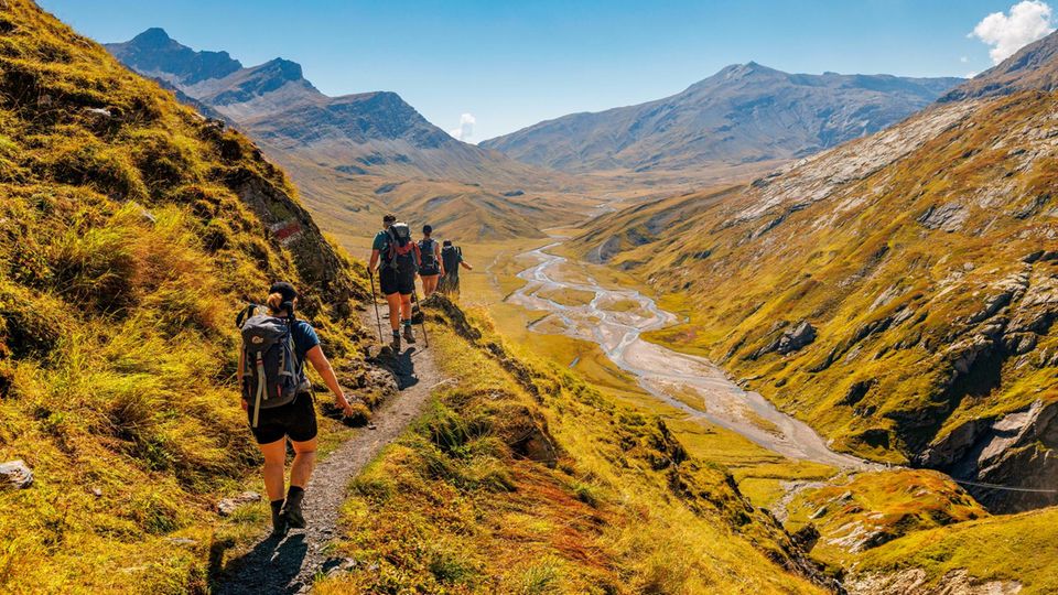 Der Rein da Sumvitg, ein Zufluss des Rheins, windet sich tief unterhalb der Wandernden in Schleifen durch das Tal