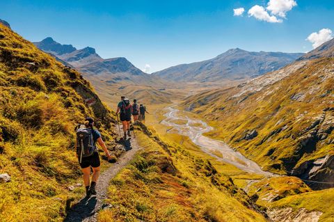 Der Rein da Sumvitg, ein Zufluss des Rheins, windet sich tief unterhalb der Wandernden in Schleifen durch das Tal