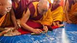 Der Dalai Lama lässt Sand durch einen Trichter rieseln und formt so die ersten Linien eines Kalachakra-Mandalas. Es zeigt die bunten Paläste buddhistischer Gottheiten. Etwa 150.000 Pilger wohnten dem mehrtätigen Ritual 2012 im indischen Ladakh bei. Danach werden die Sandbilder mit einem Pinsel wieder verwischt, ein Symbol für die Vergänglichkeit aller Dinge. 