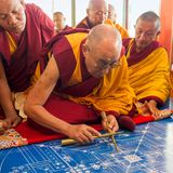 Der Dalai Lama lässt Sand durch einen Trichter rieseln und formt so die ersten Linien eines Kalachakra-Mandalas. Es zeigt die bunten Paläste buddhistischer Gottheiten. Etwa 150.000 Pilger wohnten dem mehrtätigen Ritual 2012 im indischen Ladakh bei. Danach werden die Sandbilder mit einem Pinsel wieder verwischt, ein Symbol für die Vergänglichkeit aller Dinge. 