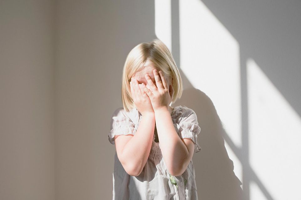 Ein kleines Mädchen hält sich die Hände vors Gesicht 1.4993