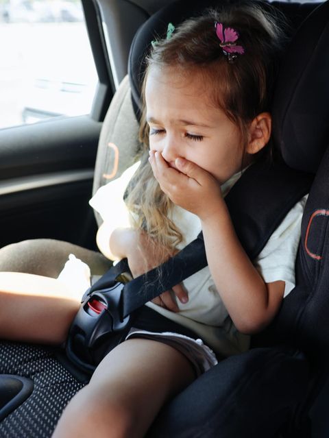 Kleines Mädchen im Auto hält sich die Hand vor den Mund