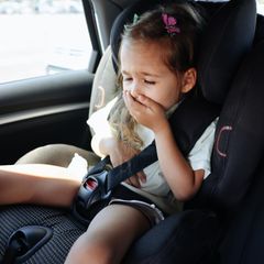 Kleines Mädchen im Auto hält sich die Hand vor den Mund
