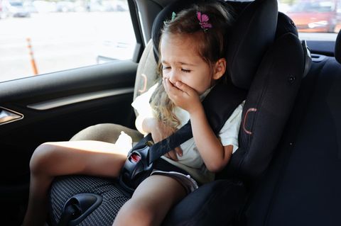 Kleines Mädchen im Auto hält sich die Hand vor den Mund