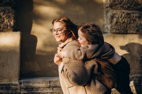 Mutter trägt ihren Sohn Huckepack