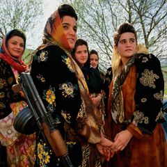 Junge, bewaffnete Kurdinnen in traditioneller Kleidung besuchen eine Hochzeit