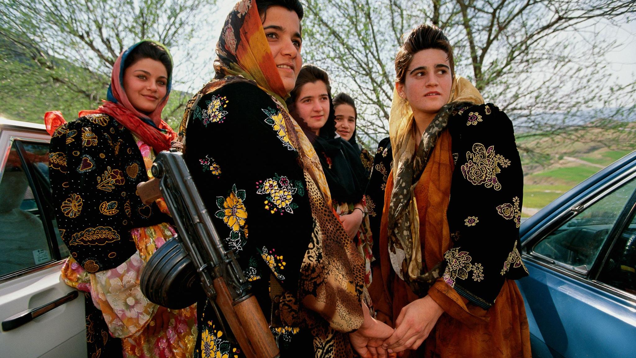 Junge, bewaffnete Kurdinnen in traditioneller Kleidung besuchen eine Hochzeit