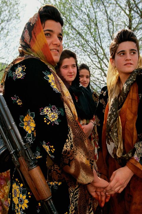 Junge, bewaffnete Kurdinnen in traditioneller Kleidung besuchen eine Hochzeit