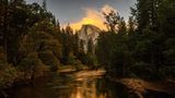 Reflection of Half Dome in Merced River presents a captivating scene where the iconic Half Dome of Yosemite National Park is mirrored in the tranquil waters of the Merced River. This breathtaking image captures the grandeur of the granite rock formation and the surrounding landscape, enhanced by the stillness of the river that allows for a perfect reflection. The play of light and shadow adds depth and dimension to the composition, creating a serene and picturesque view of one of nature's marvels.