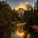 Reflection of Half Dome in Merced River presents a captivating scene where the iconic Half Dome of Yosemite National Park is mirrored in the tranquil waters of the Merced River. This breathtaking image captures the grandeur of the granite rock formation and the surrounding landscape, enhanced by the stillness of the river that allows for a perfect reflection. The play of light and shadow adds depth and dimension to the composition, creating a serene and picturesque view of one of nature's marvels.