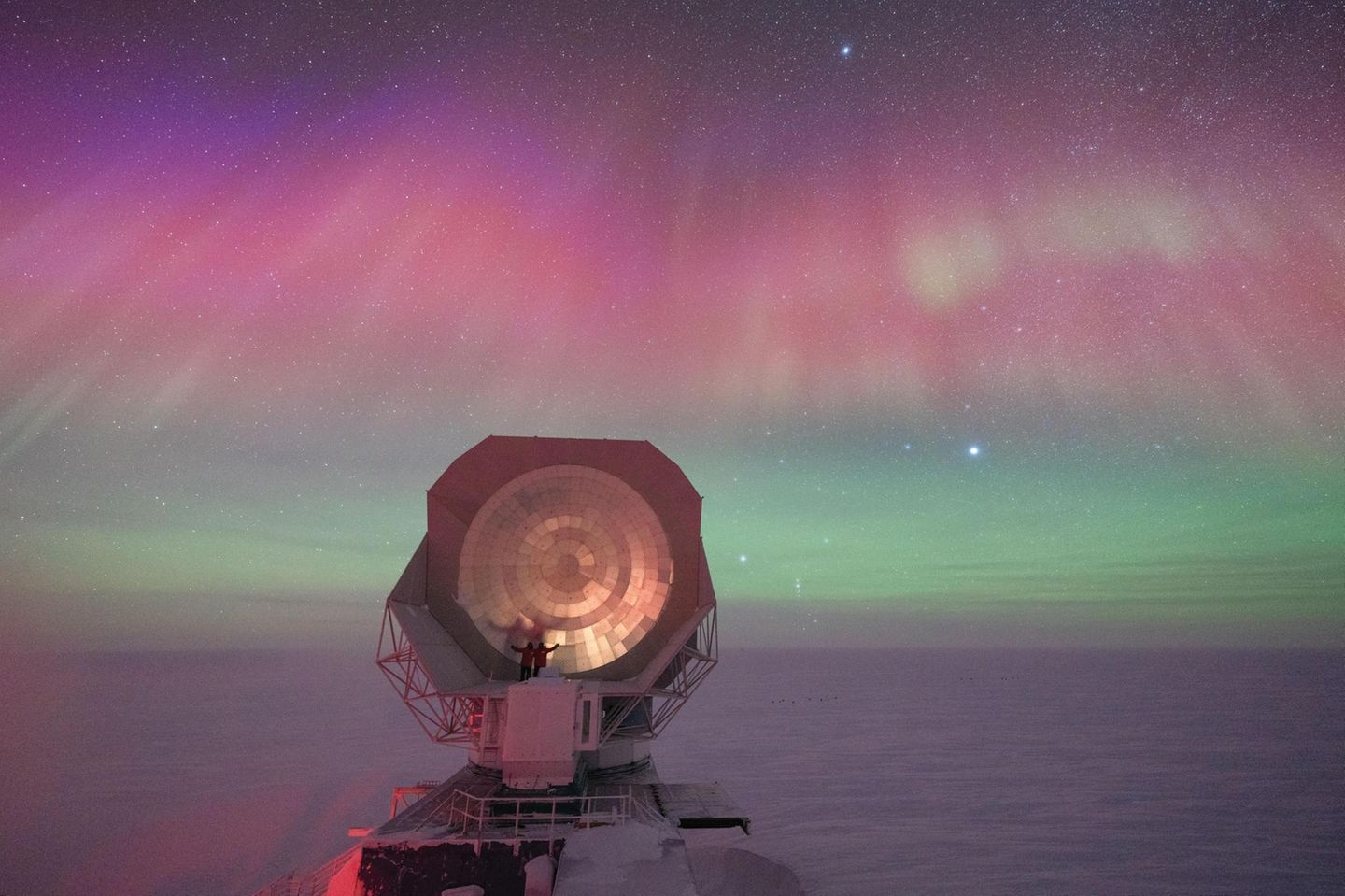 Ein riesiges Teleskop einer US-amerikanischen Forschungsstation am Südpol vor dem Hintergrund spektakulärer Polarlichter.