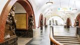 Bahnsteighalle mit Treppen, Kronleuchtern und von Statuen gesäumten, steinernen Rundbögen
