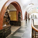 Bahnsteighalle mit Treppen, Kronleuchtern und von Statuen gesäumten, steinernen Rundbögen