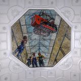 Mosaikbild von Arbeitern, über denen seitlich eine Baumaschine an einem Kranseil hängt