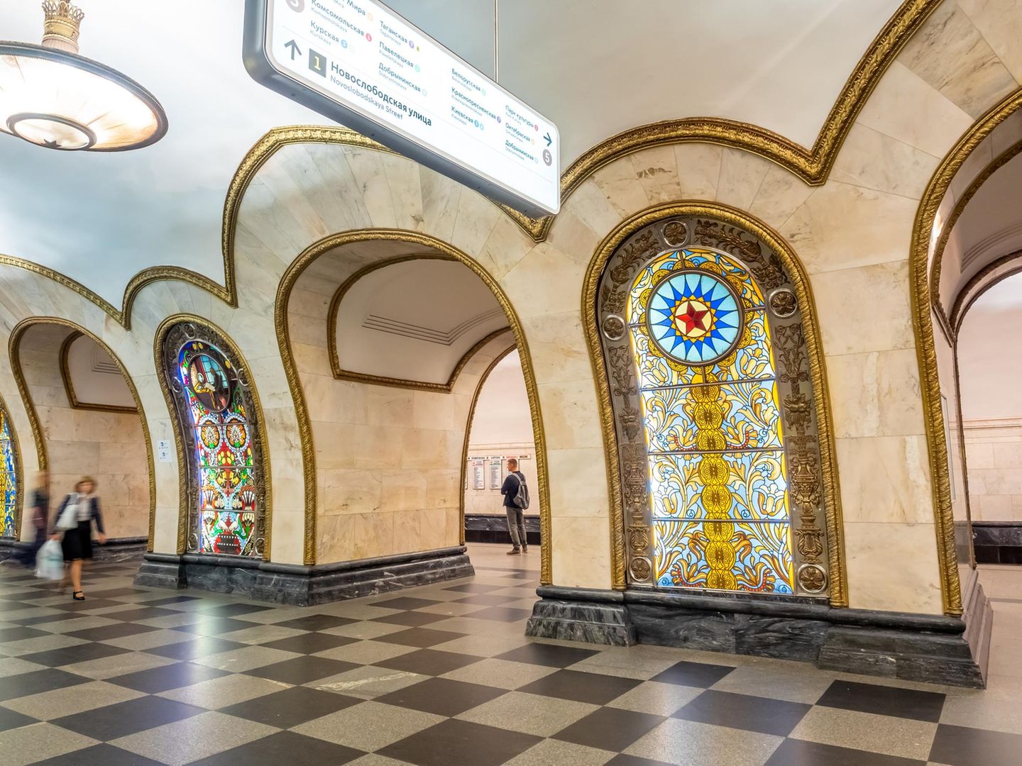 Bahnsteighalle mit Pfeilern und bunten Glasmalereien