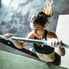 Frau macht Klimmzüge im Sportstudio