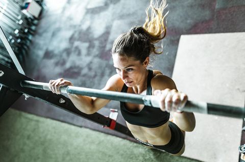 Frau macht Klimmzüge im Sportstudio