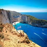 Greek flag on top of majestic cliffs, viewpoint of the famous Shipwreck Navagio Beach, Zakynthos, Greece