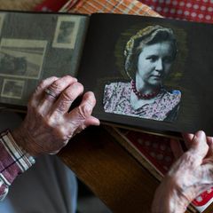 Eine alte Frau zeigt ein Bild von sich als junge Frau in einem Fotoalbum