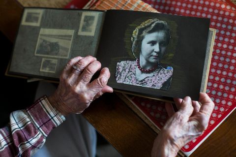 Eine alte Frau zeigt ein Bild von sich als junge Frau in einem Fotoalbum
