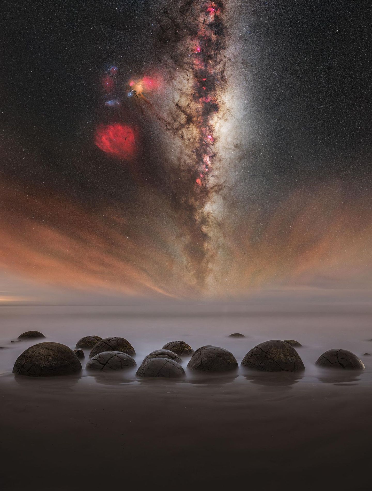 "Galaxie der Steinreihen" – Alvin Wu Die Moeraki Boulders an der Küste von Otago auf der Südinsel Neuseelands wirken wie von einem anderen Planeten: Die bis zu 2,20 Meter großen Felsen sind nahezu kugelförmig und ragen bei auflaufendem Wasser teilweise aus dem Meer. Alvin Wu fotografierte die Moeraki Boulders in der Nacht, flankiert vom leuchtenden Band der Milchstraße, das sich am Horizonz mit dem atmosphärischen Leuchten auf der Wasseroberfläche vermischt.